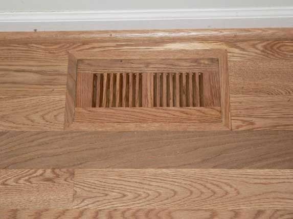 Wooden floor vent flush with hardwood flooring.