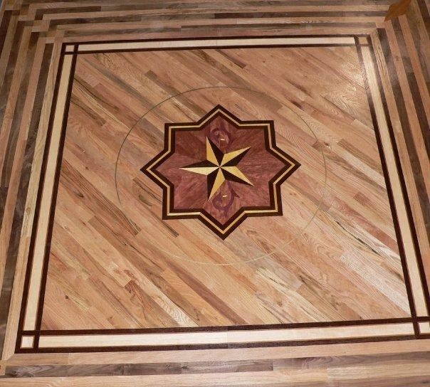 Wooden floor with a star-shaped design in the center, surrounded by square and striped borders.