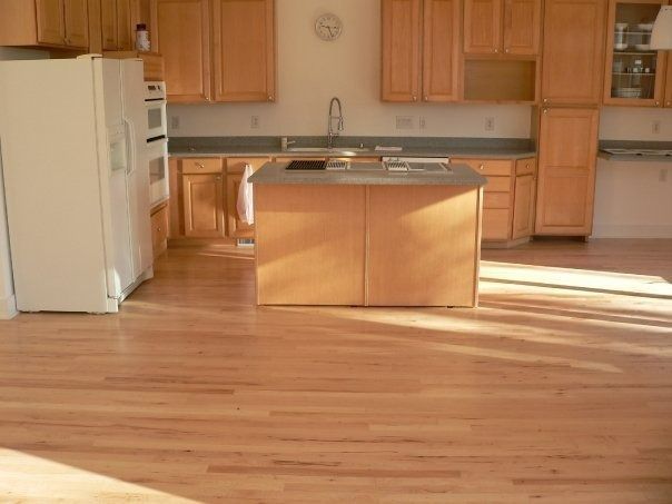 Light wood-floored kitchen with light wood cabinets, an island, and a white refrigerator.