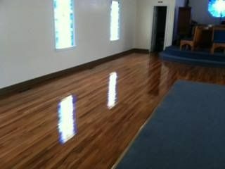Shiny wood floor in a room with windows, reflecting light and blue seating.