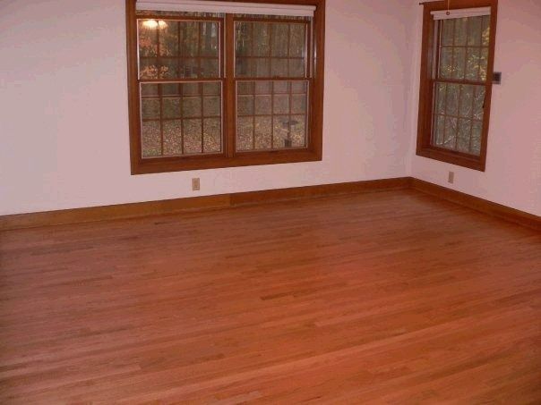 Empty room with wood floors, windows, and trim.