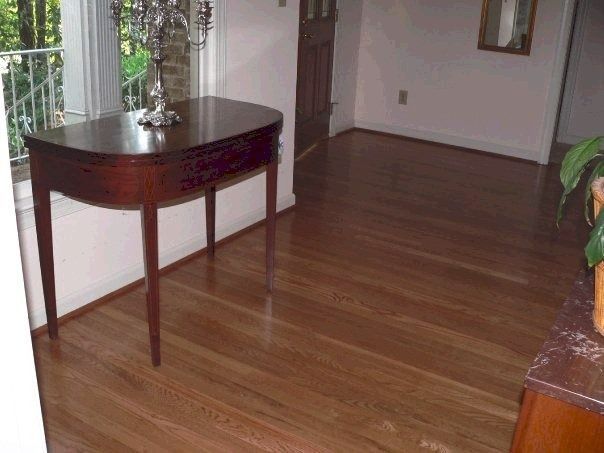 A mahogany side table with a silver sculpture, set on a hardwood floor in a well-lit room.