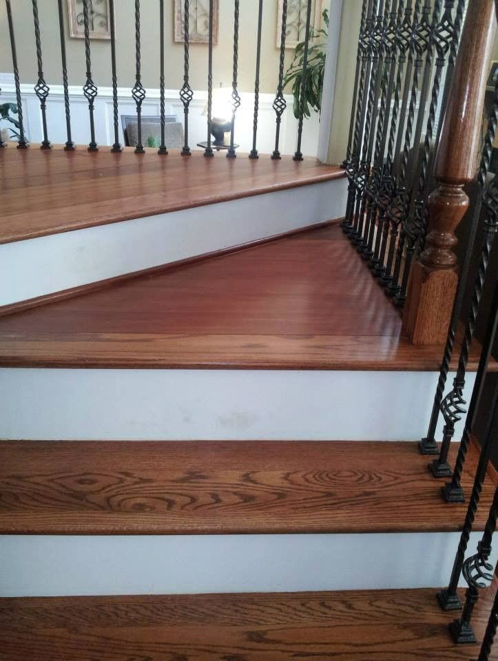 Wooden staircase with white risers, wrought iron railing, and polished wood steps.