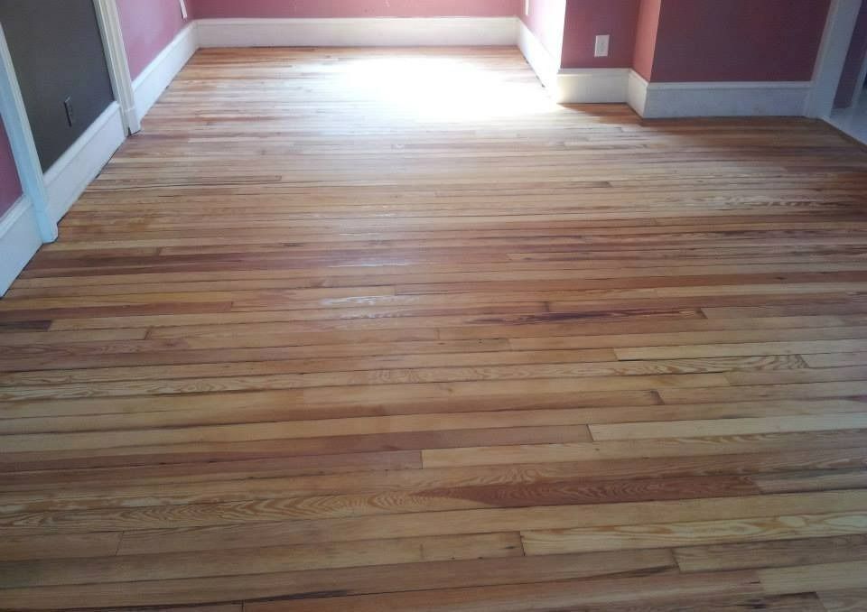 Light wood floor in a room with pink walls and white trim.