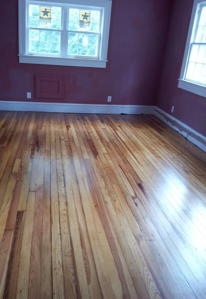 Wooden floors in a room with purple walls and white trim. Two windows in the background.