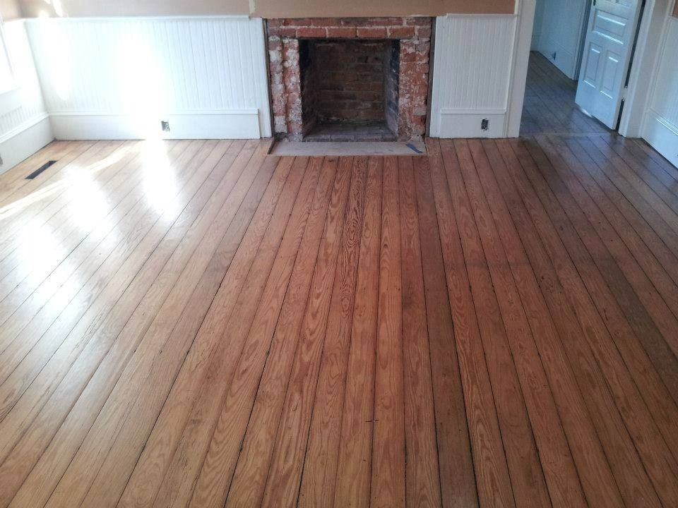 Hardwood floor in a room with a fireplace and white paneling.