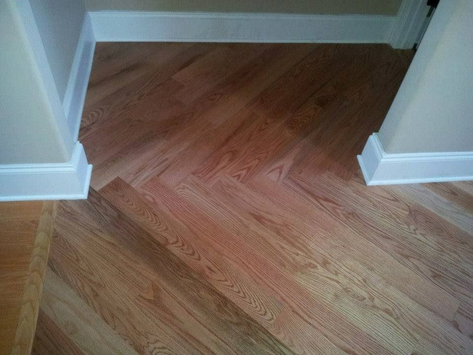 Herringbone wood floor in doorway, bordered by white trim and light beige walls.