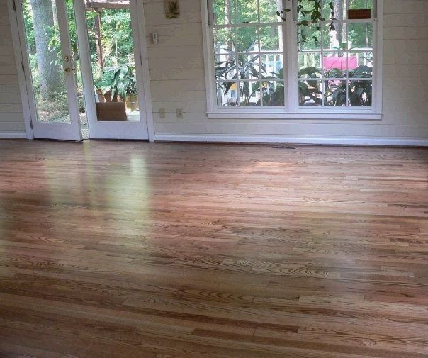 Hardwood floor in a sunlit room with French doors and a large window overlooking greenery.