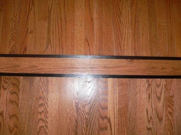 Hardwood floor with a decorative strip of wood with black borders.