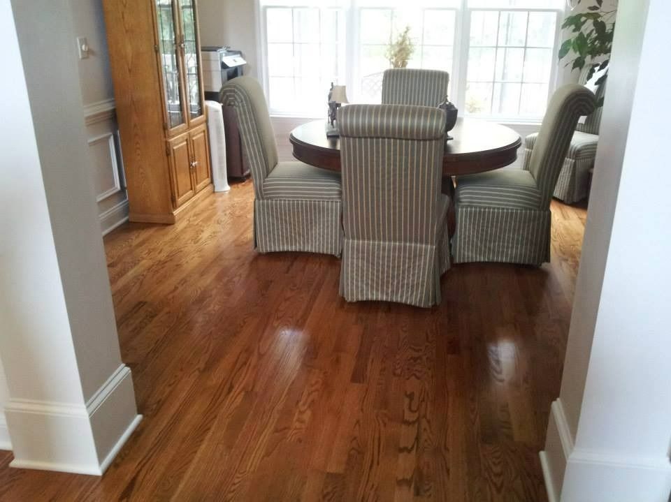 Hardwood floors in a dining room with a round table and upholstered chairs; a wooden hutch is visible.