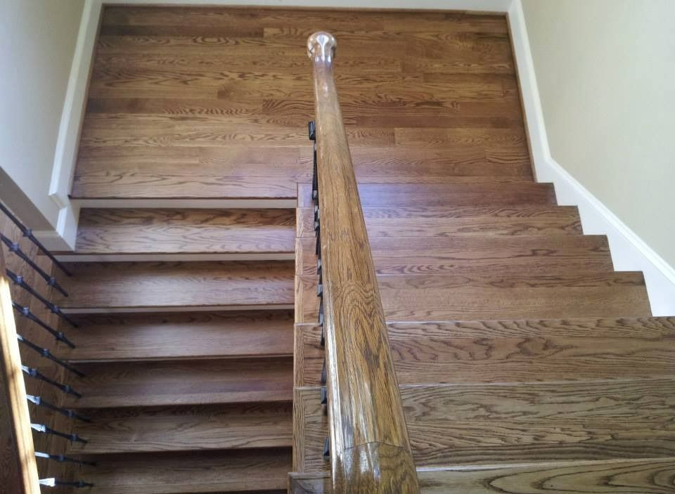 Wooden staircase with a wooden handrail, against a wall of wooden planks.