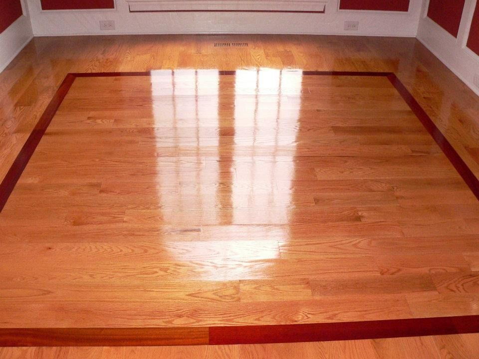 Polished wood floor with a dark border, reflecting light from a window.