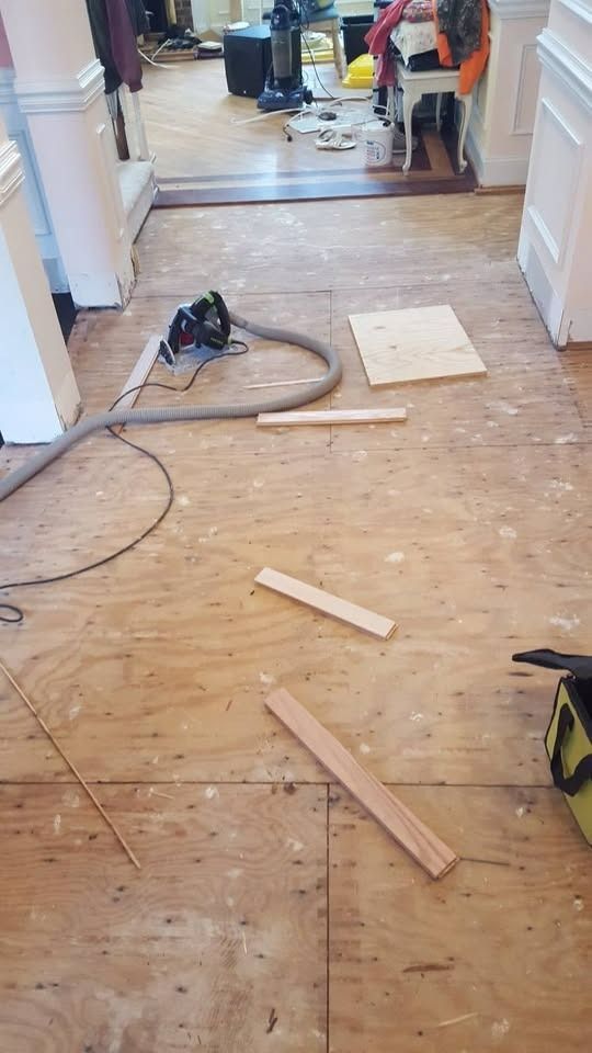 Construction site: wood floor, vacuum, and wood pieces scattered in a doorway.
