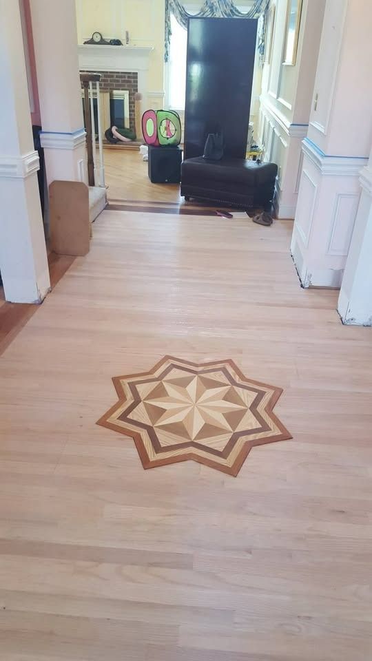 Wood hallway with starburst inlay design on floor.