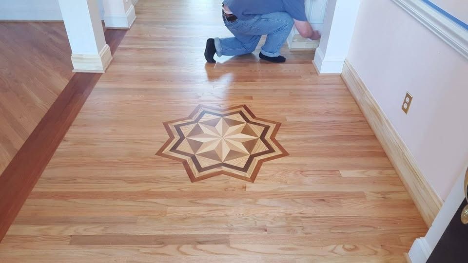 Hardwood floor with an inlaid starburst design; person installing the floor.