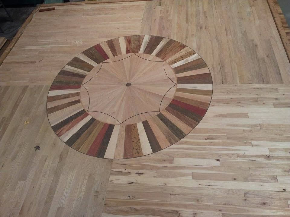 Wood floor with a circular inlaid design of various colored wood pieces.