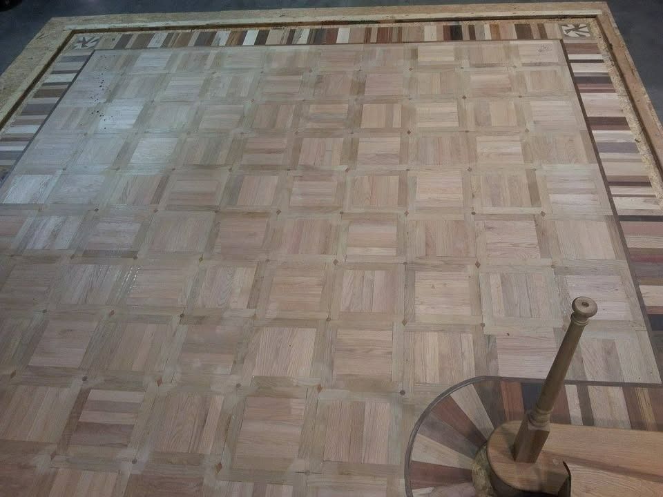 Wooden parquet floor with a decorative border, and a spiral staircase in the corner.