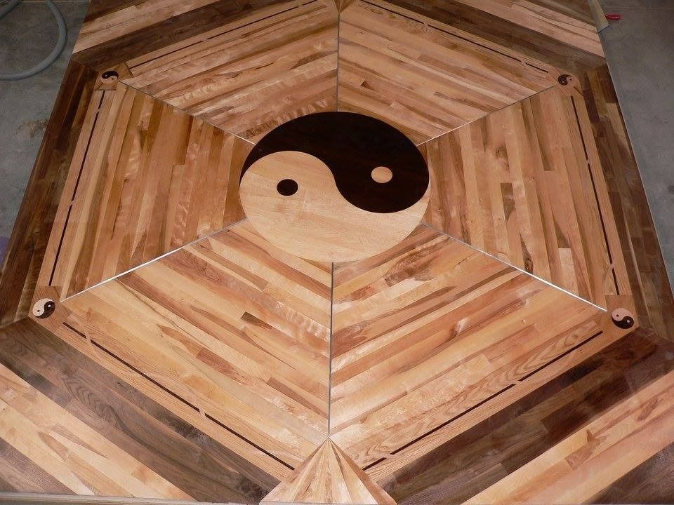 Wooden table with a Yin-Yang symbol at center, surrounded by a geometric pattern of wood planks.