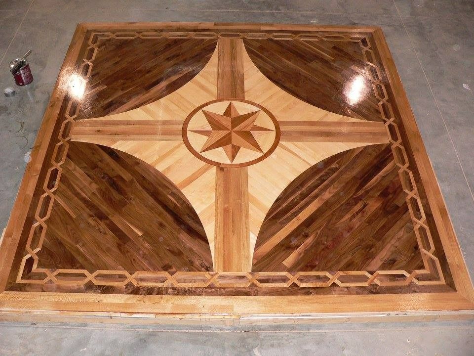 Intricate hardwood floor inlay with a compass rose design in varying wood tones, bordered by a decorative pattern.