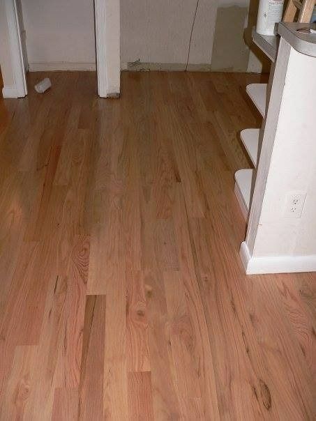 Hardwood floor in a room, showing varying shades of brown and pink. White pillars and shelves are visible.