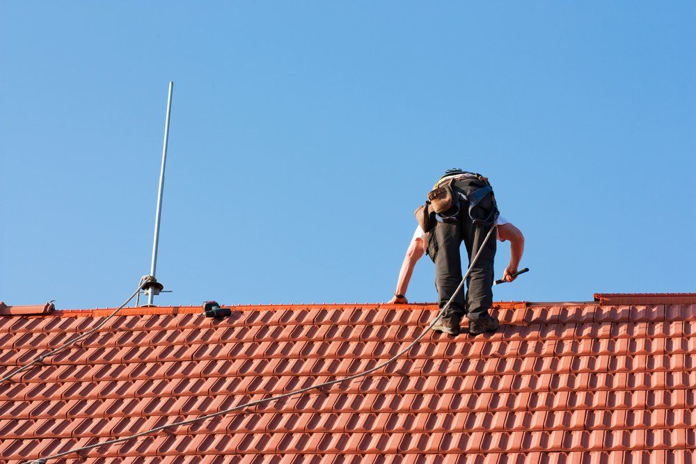 Roofer Finishing Laying the Tiles on the Roof of a Building — Second-Hand Roof Tiles in Wyong, NSW