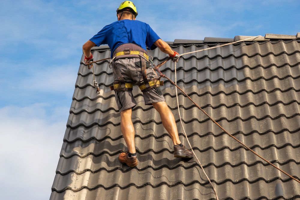 Man On A Roof Performing Roof Paint Maintenance 