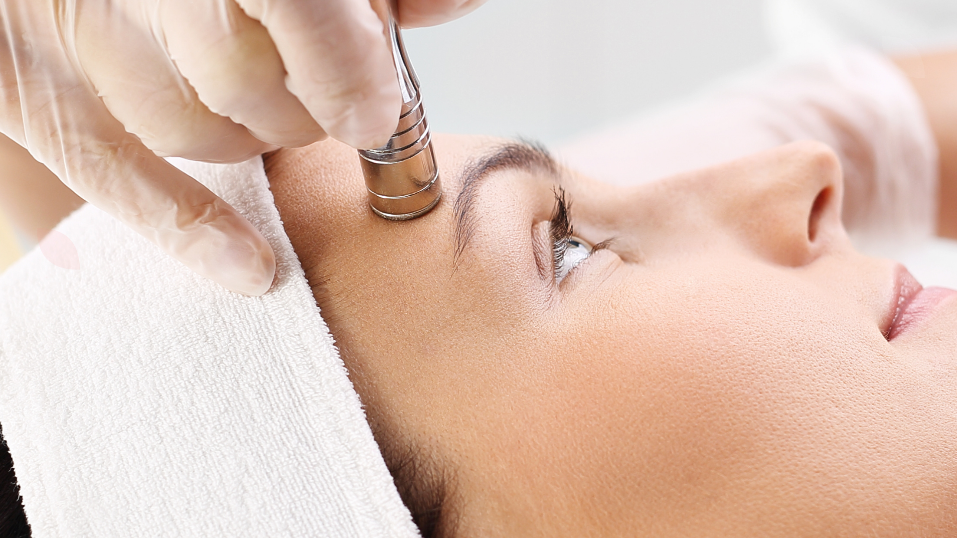 Woman receiving a facial treatment with a dermabrasion tool on her forehead.