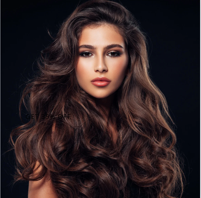 Woman with long, wavy brown hair and professional makeup against a black backdrop.