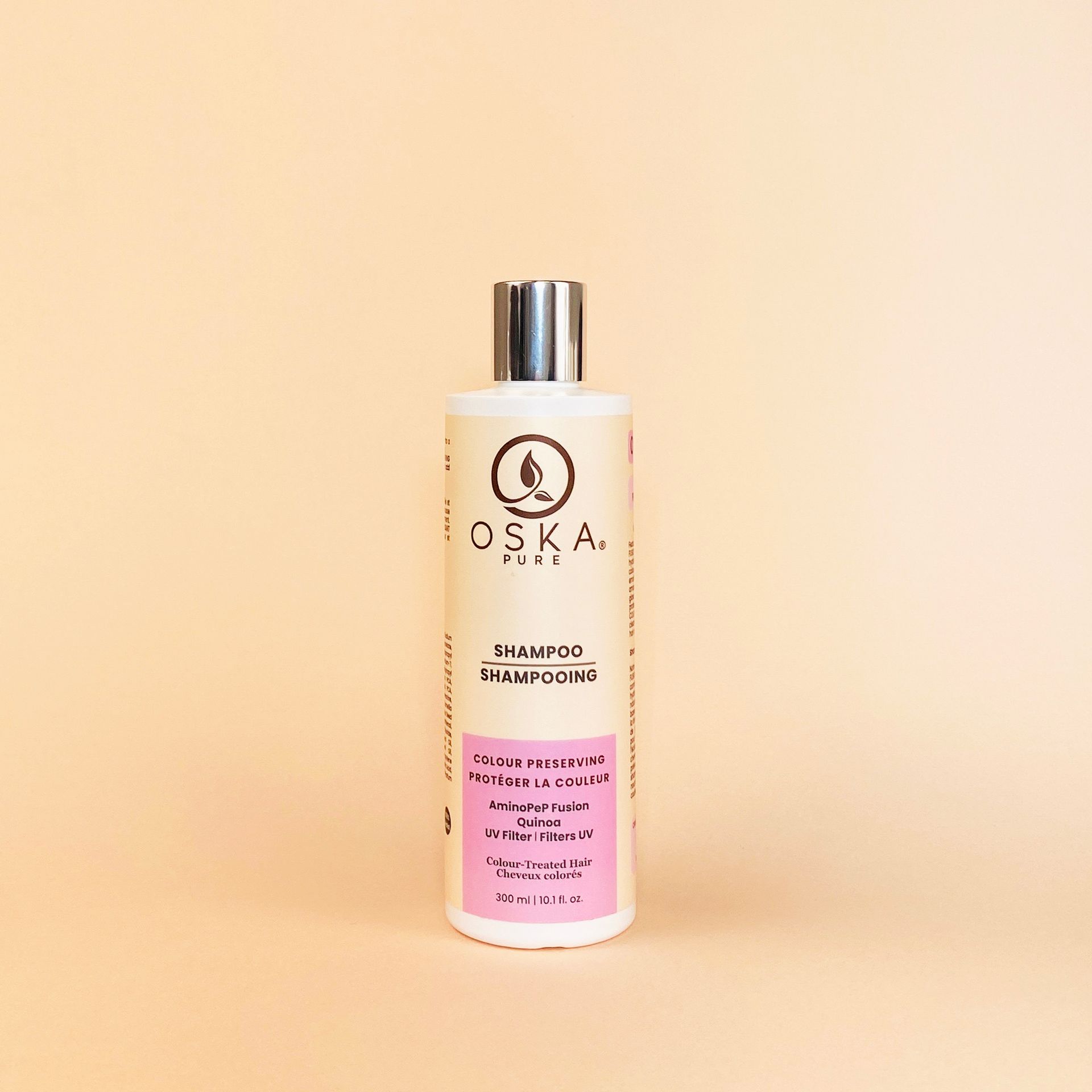 A bottle of OSKA hair shampoo with a silver cap, against a beige background.