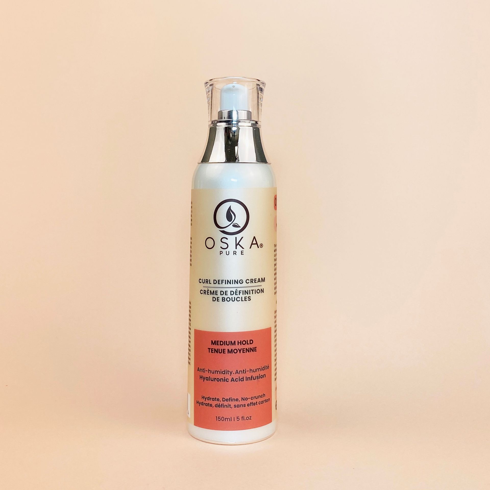 Bottle of OSKA PURE skin serum with pump on a light orange background.