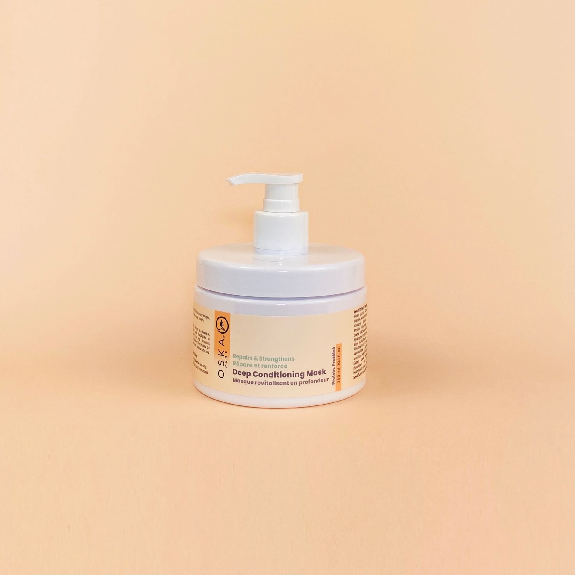White jar with a pump dispenser on a light orange background. The jar has labels with text.