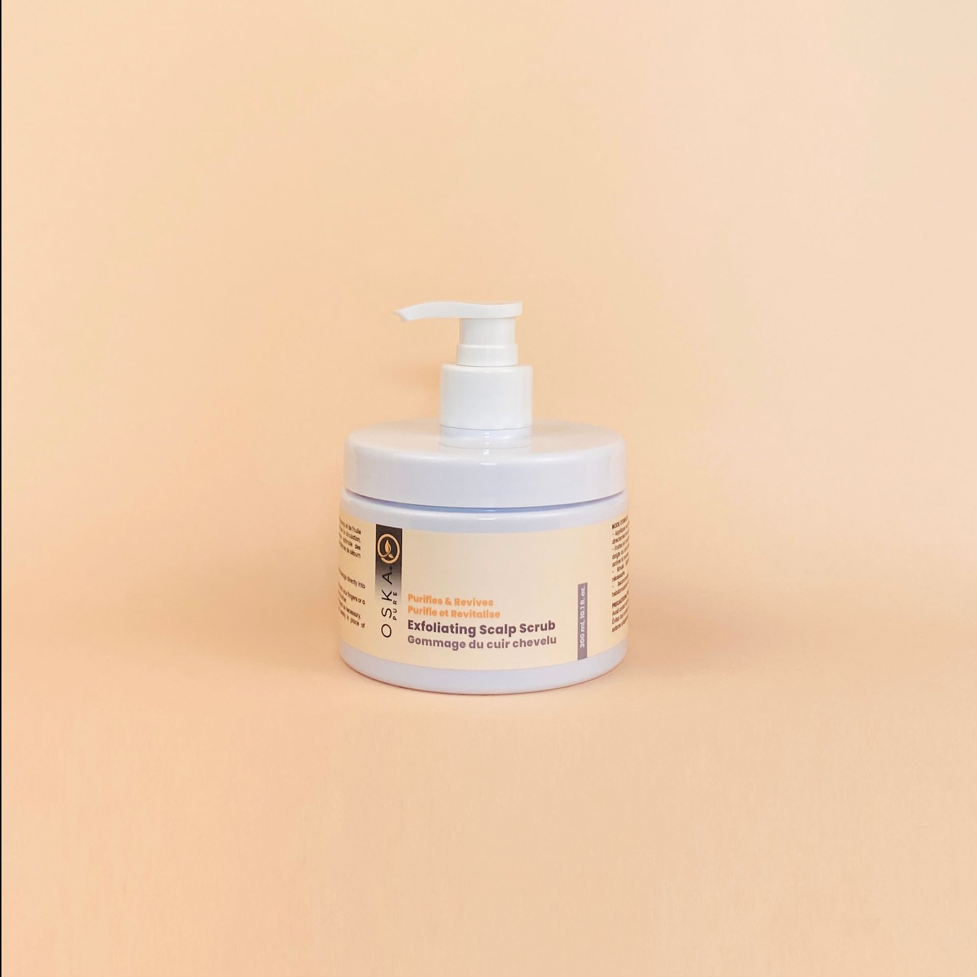 White jar of lotion with a pump dispenser on an orange background.