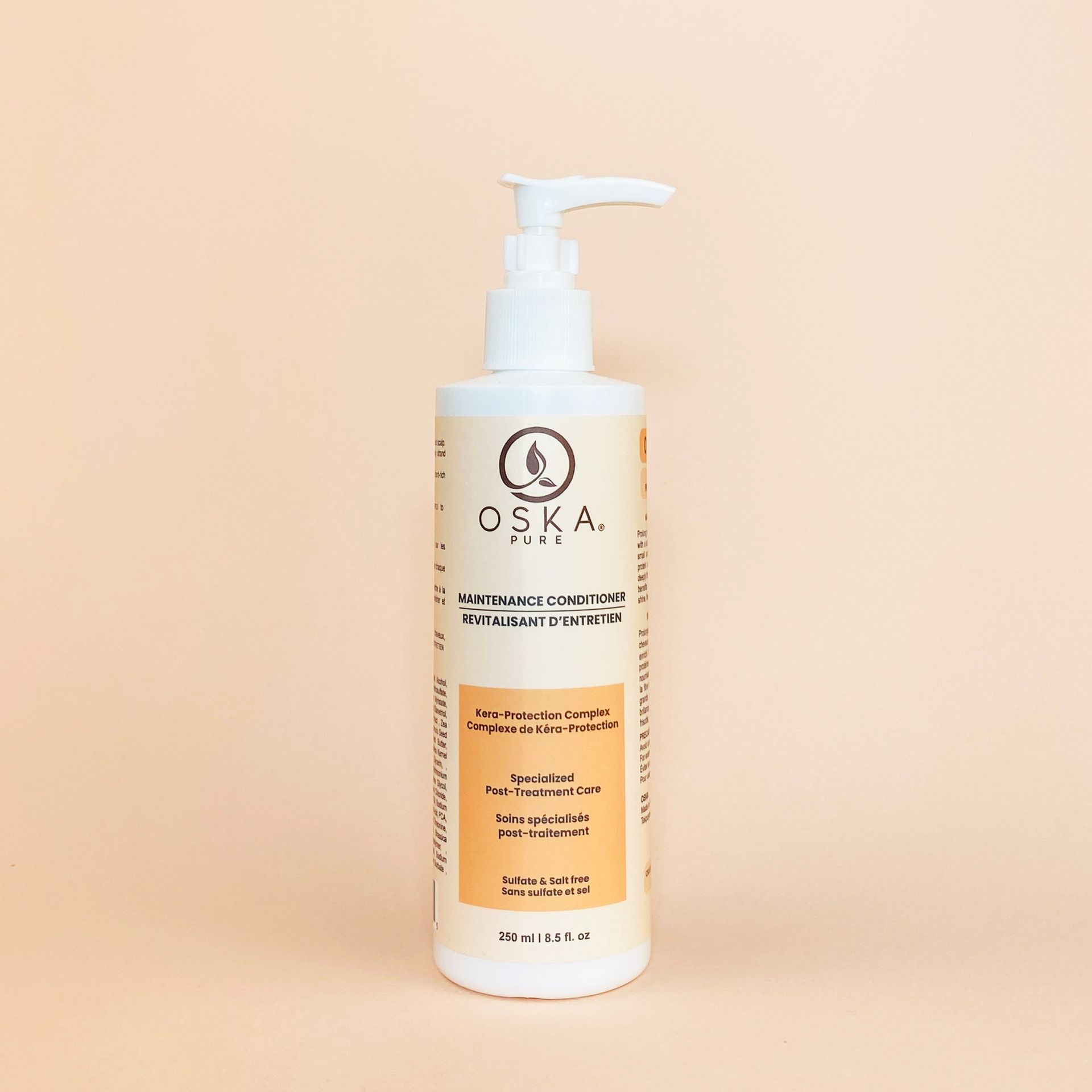 White OSKA shampoo bottle with a pump against a peach background.