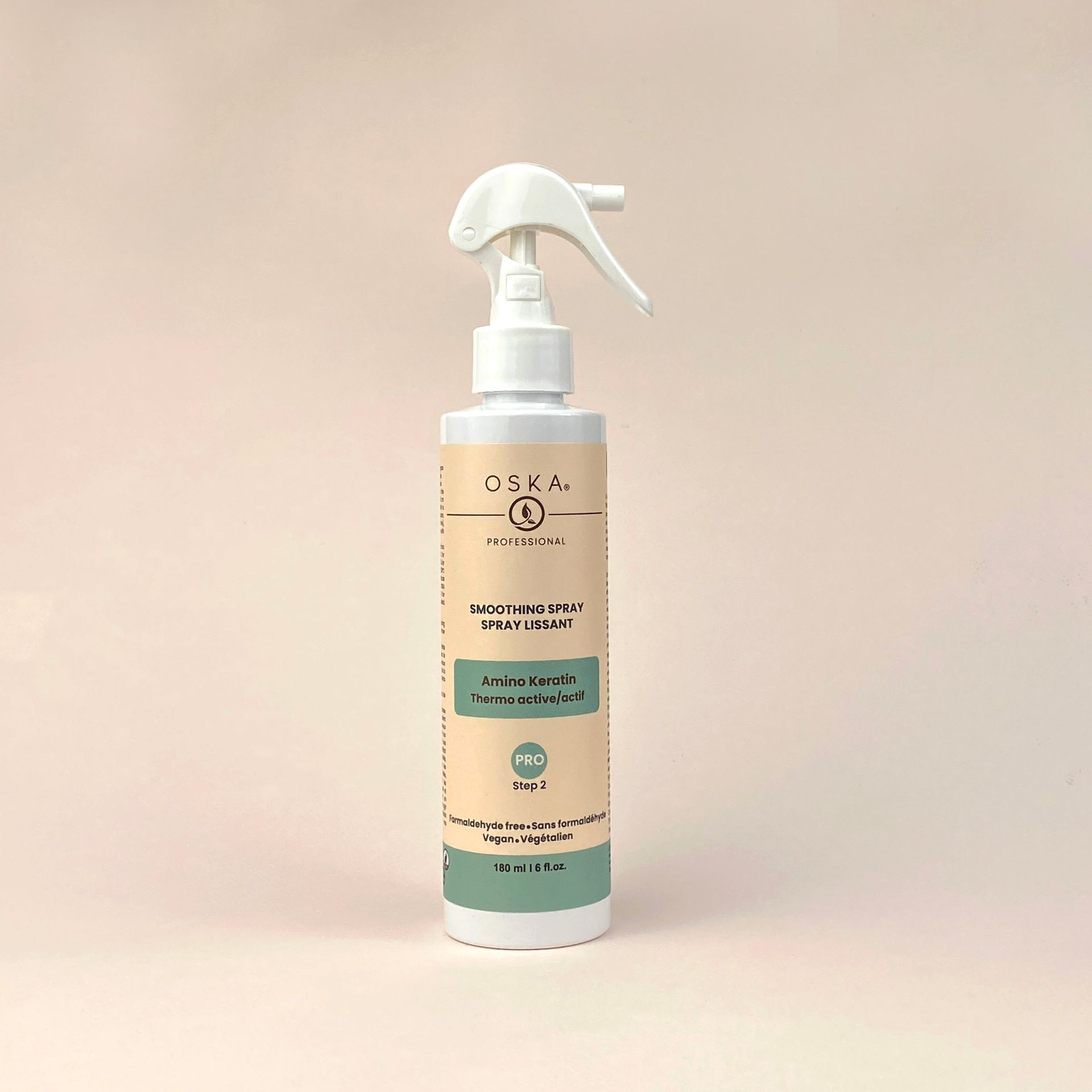 White spray bottle with a label against a light pink backdrop.