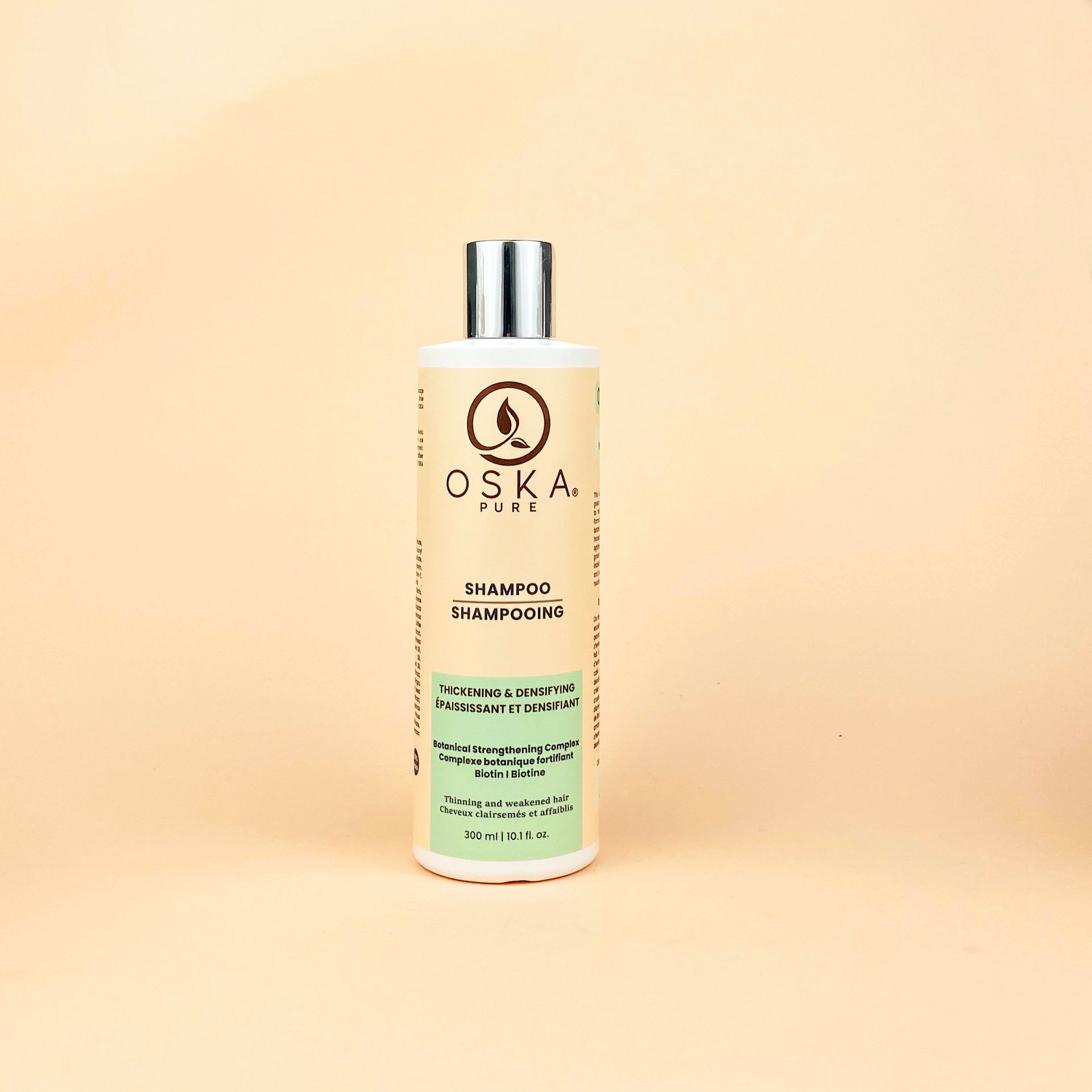 Bottle of OSKA hair shampoo on a cream-colored background.