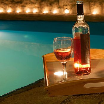 Una bottiglia di vino è appoggiata su un vassoio di legno accanto a un bicchiere di vino