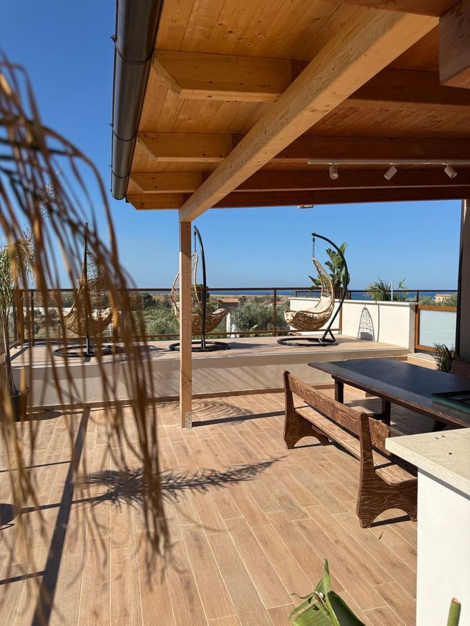 Un ponte di legno con tavolo e sedie sotto un tetto di legno