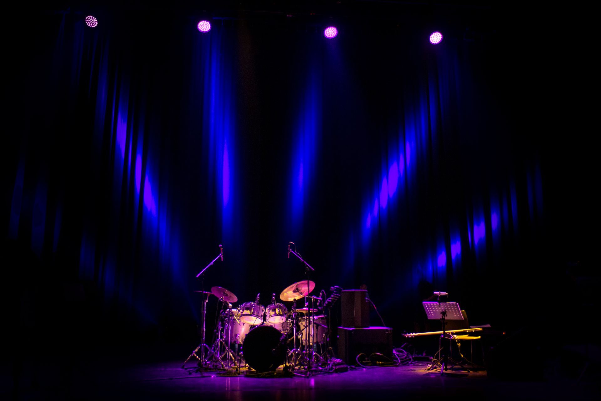 Una batteria è su un palco con luci viola dietro.
