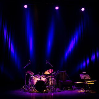 Una batteria è su un palco con luci viola.