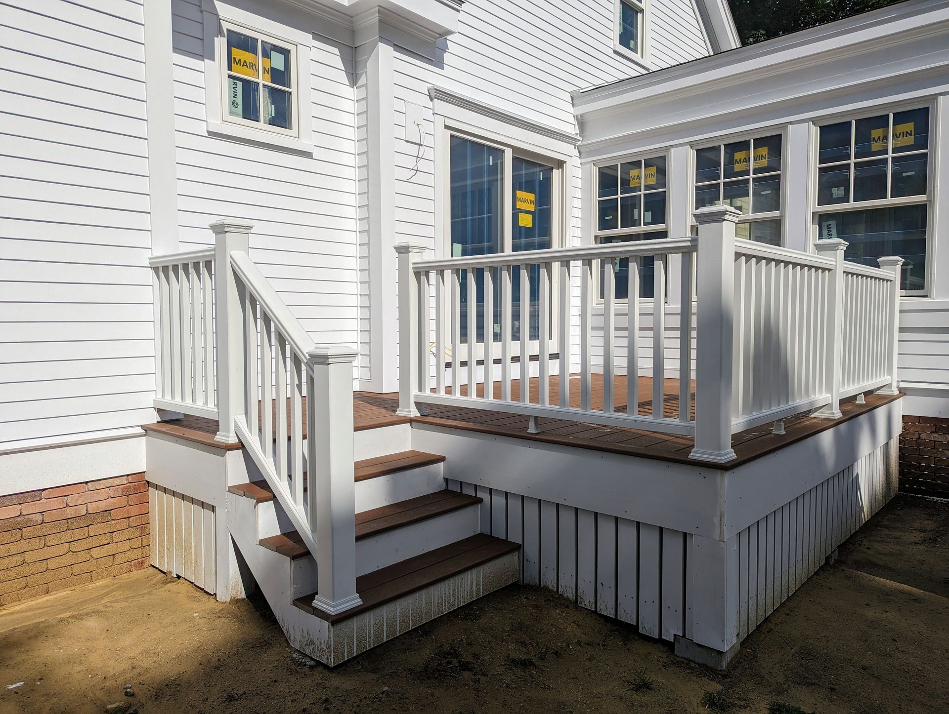 A white house with a wooden deck and stairs