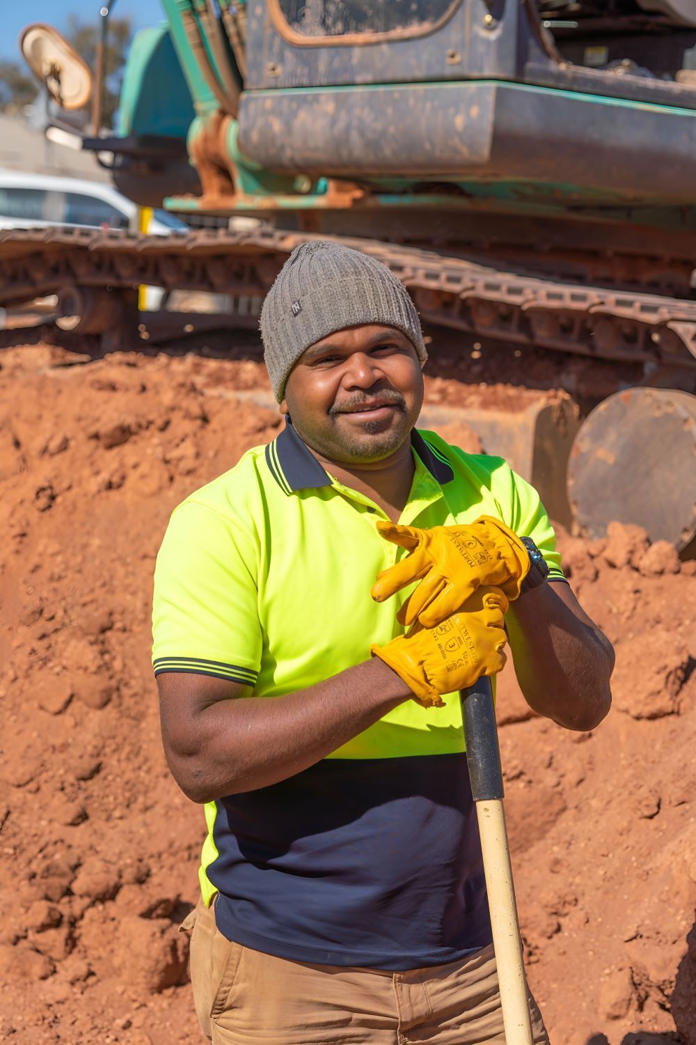 A Man Is Holding a Shovel in Front of A Bulldozer — ASPLUM & CIVIL in Alice Springs, NT