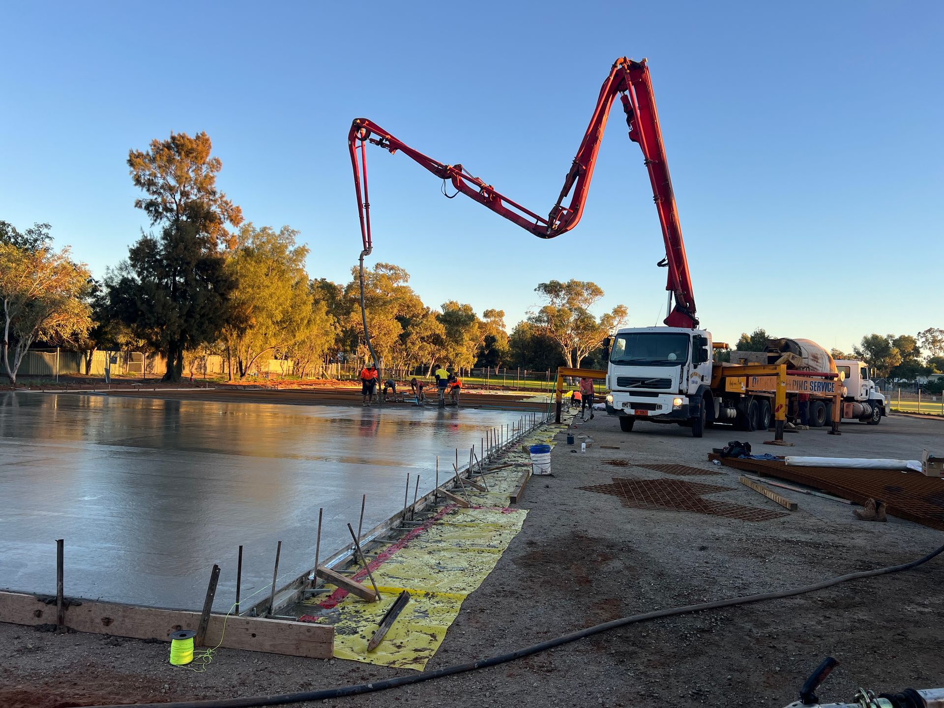Concrete being poured by a pump truck at a construction site. Workers are present near the wet concrete — ASPLUM & CIVIL In Alice Springs, NT