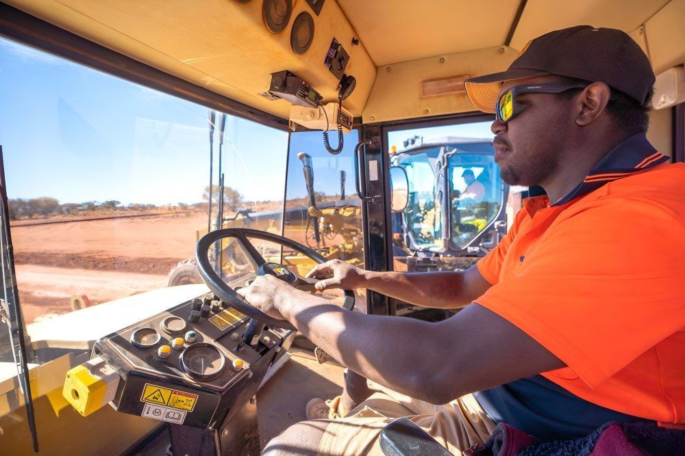 A Man Is Driving a Bulldozer on A Dirt Road — ASPLUM & CIVIL In Alice Springs, NT