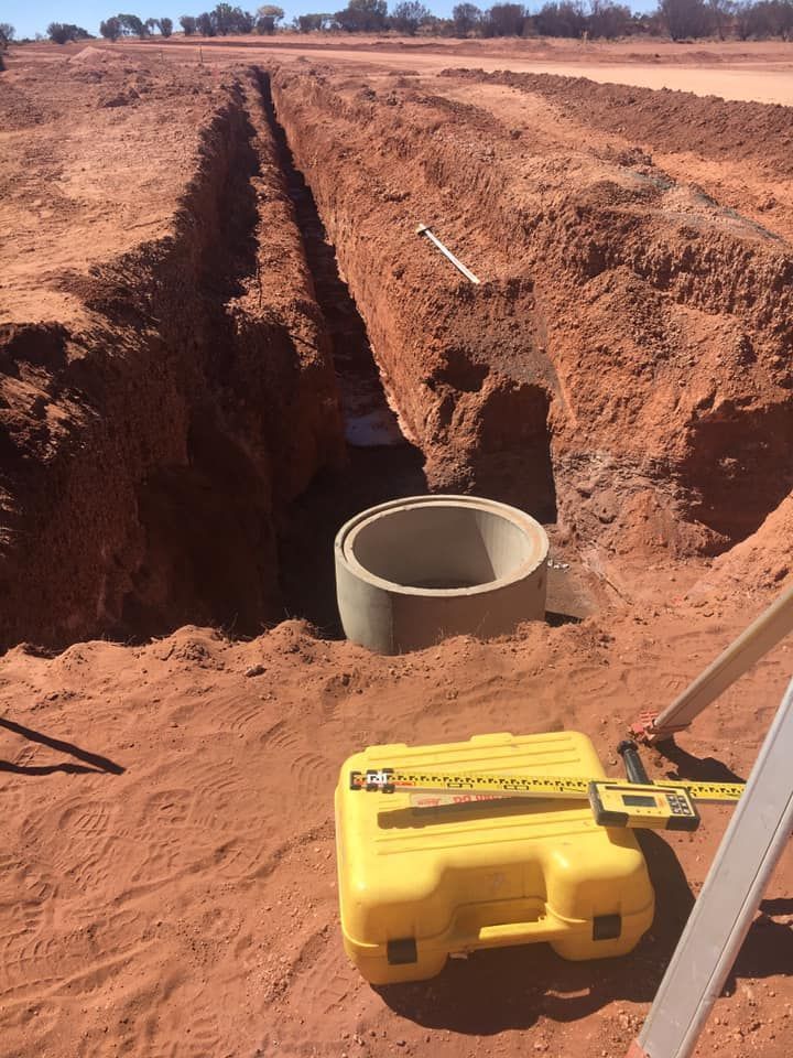 A Yellow Box is Sitting in the Dirt Next to a Measuring Tape — ASPLUM & CIVIL In Alice Springs, NT