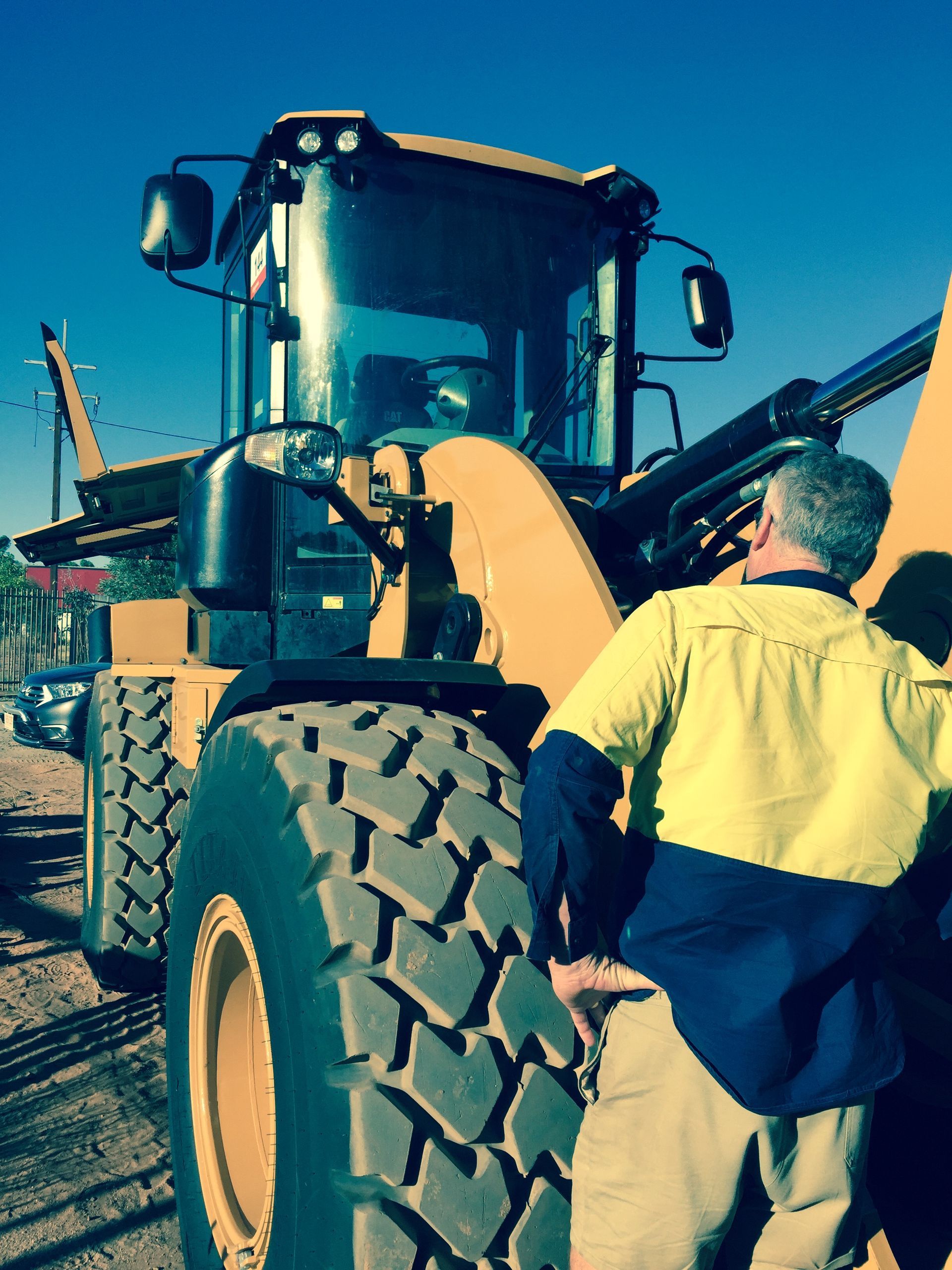 A man in high vis is standing next to a digger — ASPLUM & CIVIL In Alice Springs, NT
