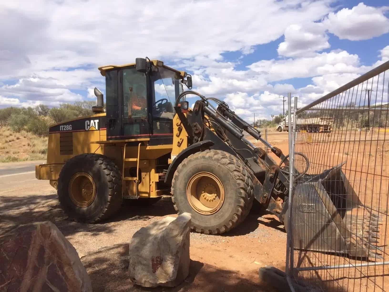 A Bulldozer is Parked in a Dirt Field Next to a Fence — ASPLUM & CIVIL In Alice Springs, NT