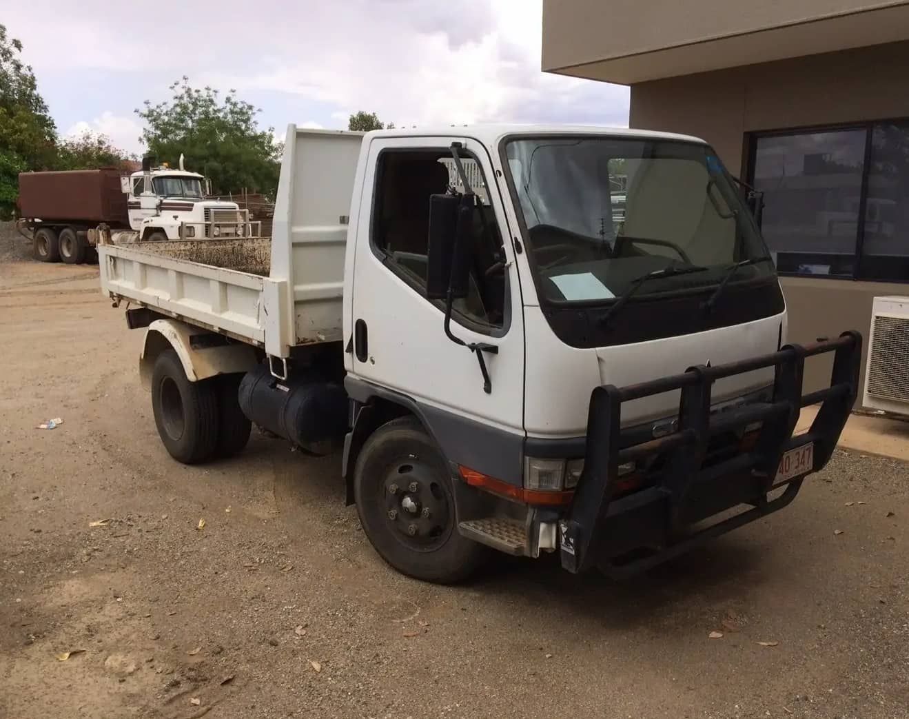 A White Dump Truck is Parked in Front of a Building — ASPLUM & CIVIL In Alice Springs, NT