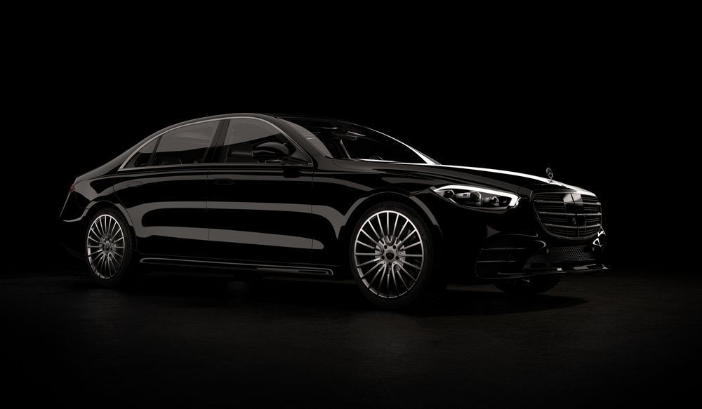 A black mercedes benz s class is parked in a dark room.