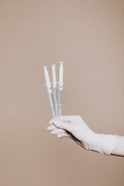 A person is holding three syringes in their hand.