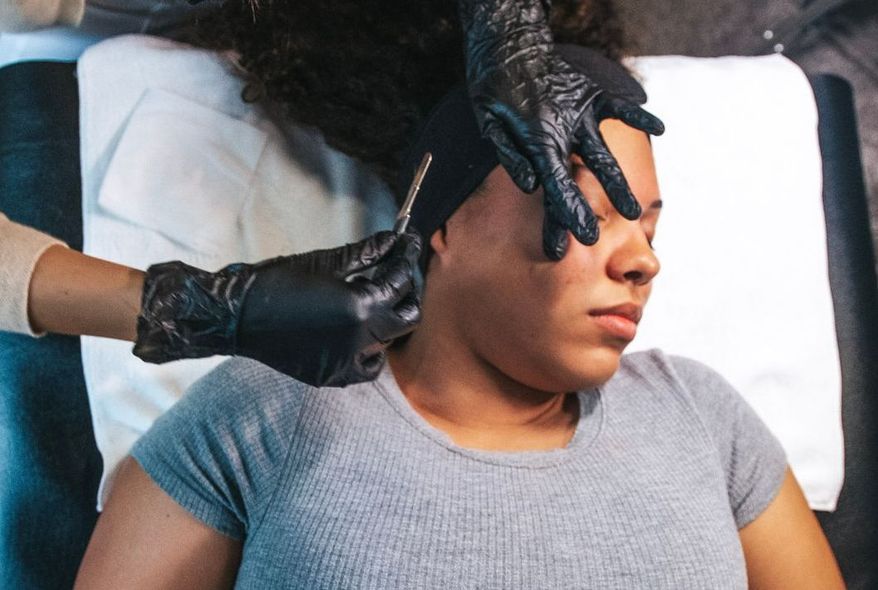 A woman is laying on a bed getting a facial treatment.